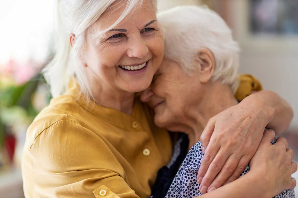 Two older adults sharing a comforting moment that reflects the Emerald Crest memory care model focused on connection, dignity, meaningful engagement, and quality of life.
